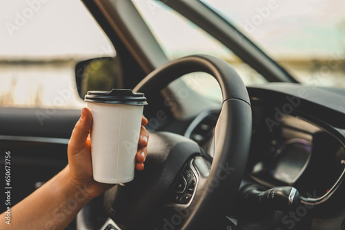 Paper cup with coffee in hand, traveling by car