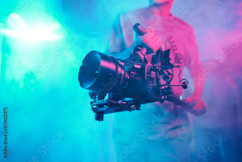 Tableau sur toile Cameraman shooting content with professional camera among smoke in photo studio