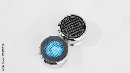 A clean new faucet aerator rotates on a white background. Water tap regulator for more efficient use of water or water flow regulator.