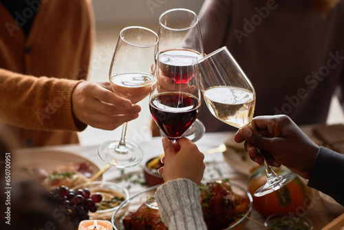Fotografiet Closeup of group of people toasting with wine glasses at festive dinner table ce