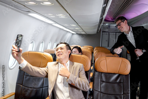 Senior businessman holding mobile phone to take selfie in comfortable seat inside airplane, male passenger on business trip in aircraft, businesspeople traveling with airline transportation. © Stella