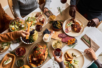 High angle view at diverse group of friends enjoying homemade food at festive dinner table with roasted turkey or chicken, copy space