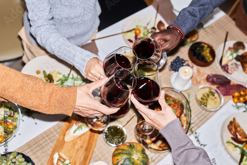 Canvas Print High angle closeup of friends toasting with red wine glasses while celebrating a
