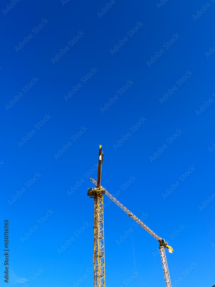 Construction site of a building in good weather. Yellow construction cranes on a working day. Construction of multi-storey buildings. Construction site of a building in good weather. Yellow construction cranes on a working day. Construction of multi-storey buildings.