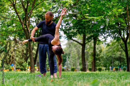 a male yoga instructor conducts a class with a woman in the park in the fresh air couple exercises spiritual practices