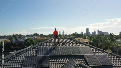 Solar panels and technician on luxury waterfront home on a sunny day.