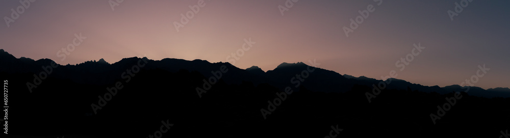 Panorama shot of mountain ridge silhouette against colorful night sky with last sur rises