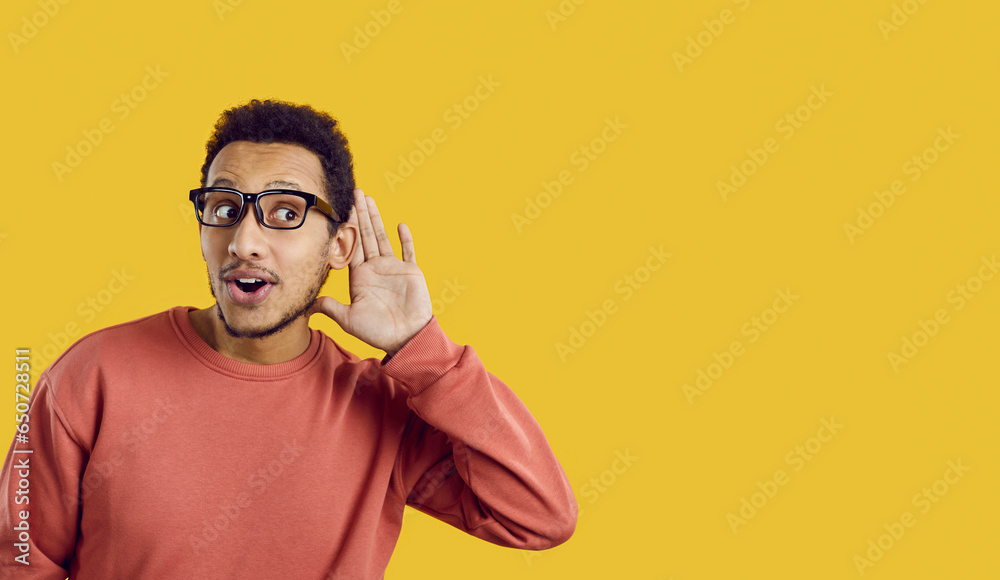 Curious man isolated on solid color text copyspace background hears talks about something, puts hand to ear, listens to someone speak, overhears top secret story, hot news, latest buzz, funny gossip - obrazy, fototapety, plakaty 