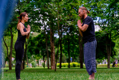 couple practicing yoga outdoors in a city park doing meditation exercises with namaste gestures people focus on mental and spiritual health