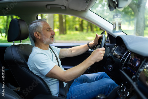 Obraz na plátně Mature man driving modern car and beep in trafic