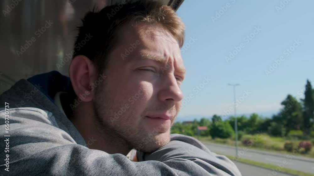 Young man looking out of train window while traveling by railway through Balkans. Male traveler looking out sleeping car window in the morning Young man looking out of train window while traveling by railway through Balkans. Male traveler looking out sleeping car window in the morning