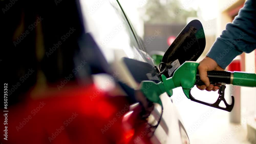 à la station essence quelqu'un fait le plein de remplissage de carburant diesel ou sans plomb