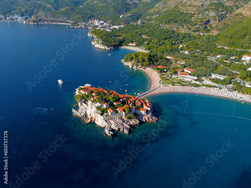 Aerial view of Sveti Stefan island and shore in a beautiful summer day, Montenegro from flying drone. Panoramic above view of Saint Stephen luxury resort. Tourism and leisure concept. Aero photography photo