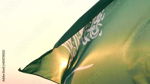 Close-up Saudi Arabia flag waving in sky against wind, beautiful sunset or sunrise outdoor backgrounds, slow motion. Concept of Saudi Arabia, Independence Day, Celebration, Holiday, Flag