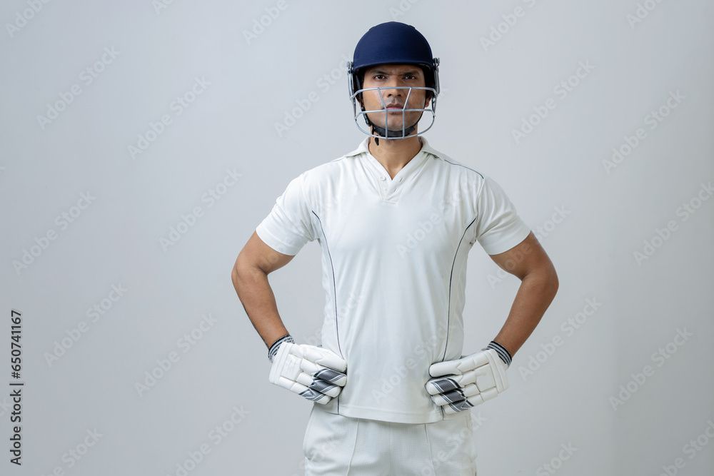portrait of indian Man in cricket dress with helmet and gloves. Cricketer portrait in studio light looking towards the camera portrait of indian Man in cricket dress with helmet and gloves. Cricketer portrait in studio light looking towards the camera