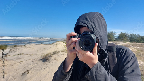 Photographer taking picture on the beach with dunes in the background © Miriana