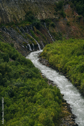 Georgia, Kazbegi region. View of green forest, waterfalls and the Terek River in the gorge. Amazing autumn landscape of the national Park. Tourist route to the Truso Valley, Caucasus mountains.