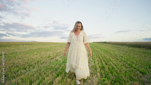 The mowed wheat field becomes a place for a woman to run freely, a moment when she surrenders to joy and unforced happiness. High quality 4k footage photo