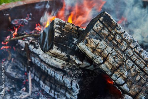 фотографія Close up of ashen logs smoking with embers and orange and yellow flames in backg