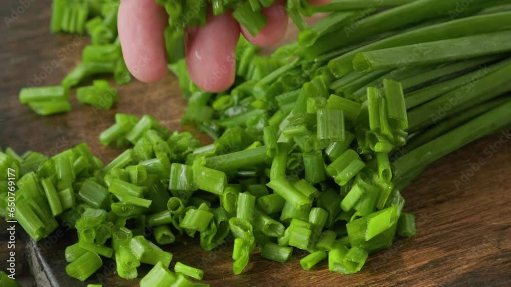 Man hand take chopped spring or green onion on wooden cutting board. Cooking food