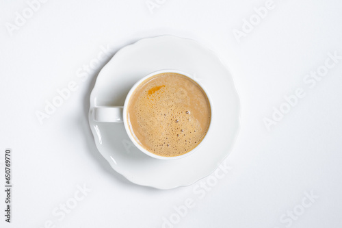 Cup of cappuccino coffee on a plain white table background. Cozy flatlay and top view. Coffee mug and breakfast routine. Minimalist concept