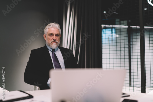 Senior businessman sitting in office with laptop