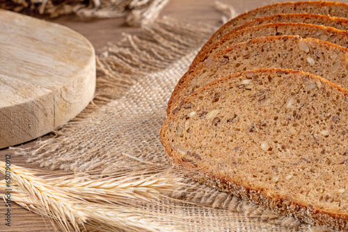 Slices of fresh rye bread with grains lie on a burlap napkin, close-up rustic style