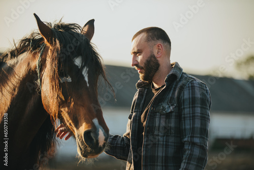 Slika na platnu A young farmer works in a paddock with horses