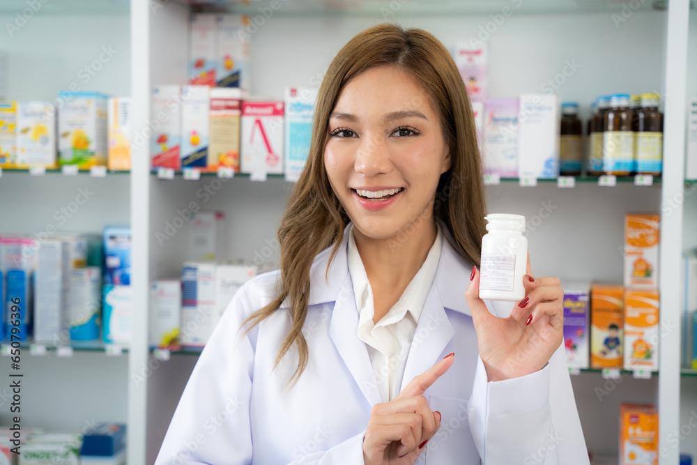 Portrait of smiling pharmacist holding drug at drugstore. She showing product to camera with smiling.