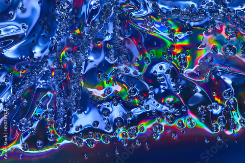 Vibrant abstract art with rainbow colors in bubbles flowing across wavy oily surface background