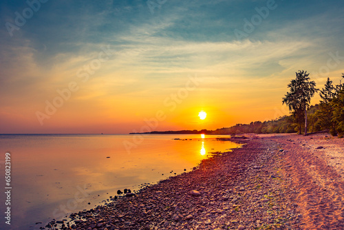 Obraz na płótnie Sunset over the sea. Cloudy sky. Rocky shore. Smooth surface of water. Russia, Europe. w salonie