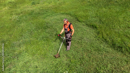 High angle view of modern gardener mows the grass with lawn mower. Space for copy photo