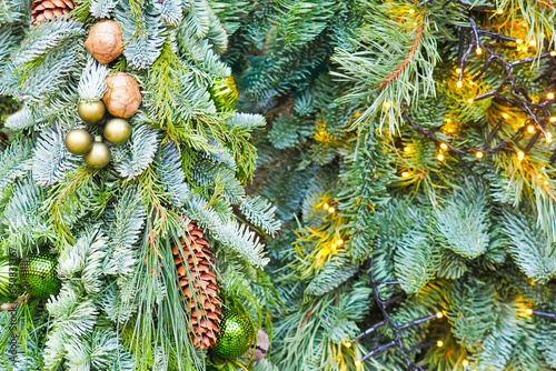 Christmas background, green fir branches decorated with garlands, balls and fir cones