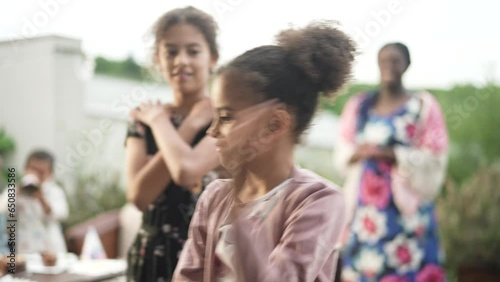 Young interracial blended family dancing and having fun at the mothers birthday party on the patio of their house