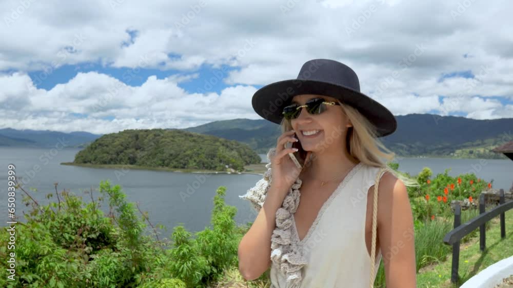 WOMAN WITH BLACK HAT WALKING AND TALKING ON CELL PHONE IN LA LAGOON DE LA COCHA OR LAKE GUAMUEZ PASTO NARIÑO