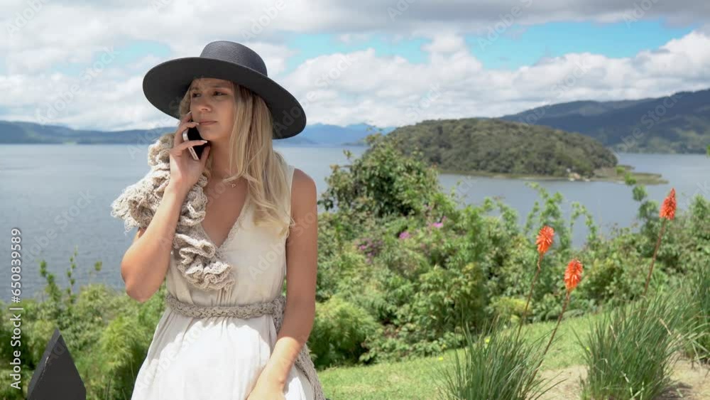 YOUNG CAUCASIAN WOMAN USING THE CELL PHONE IN A LANDSCAPE OF THE LAGOON OF LA COCHA PASTO NARIÑO. COROTA ISLAND