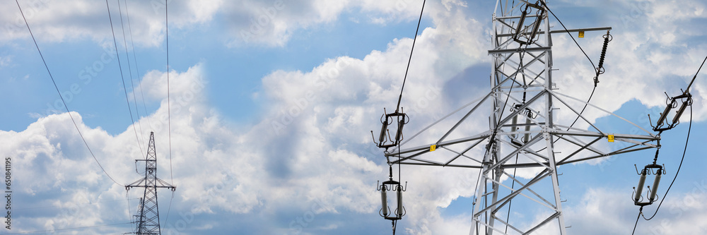 Against a panoramic background of clouds, the poles of a high-voltage overhead line can be seen. Against a panoramic background of clouds, the poles of a high-voltage overhead line can be seen.