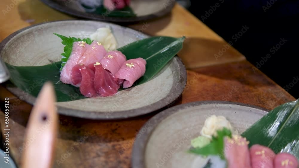 tuna fish meat with rice vermicelli on sheet spread with sauce sprinkled with gold decorations edible Lettuce leaves delicious preparation of a dish male hands in gloves cook in a restaurant. Sushiya tuna fish meat with rice vermicelli on sheet spread with sauce sprinkled with gold decorations edible Lettuce leaves delicious preparation of a dish male hands in gloves cook in a restaurant. Sushiya