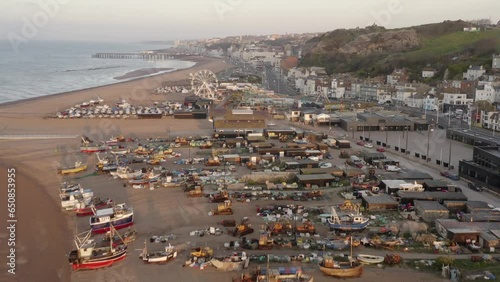 Aerial fly over beach with old boats and old town buildings background of Hastings in England. Scenic coastline towns and cities. Ferris wheel and pier in Hastings photo