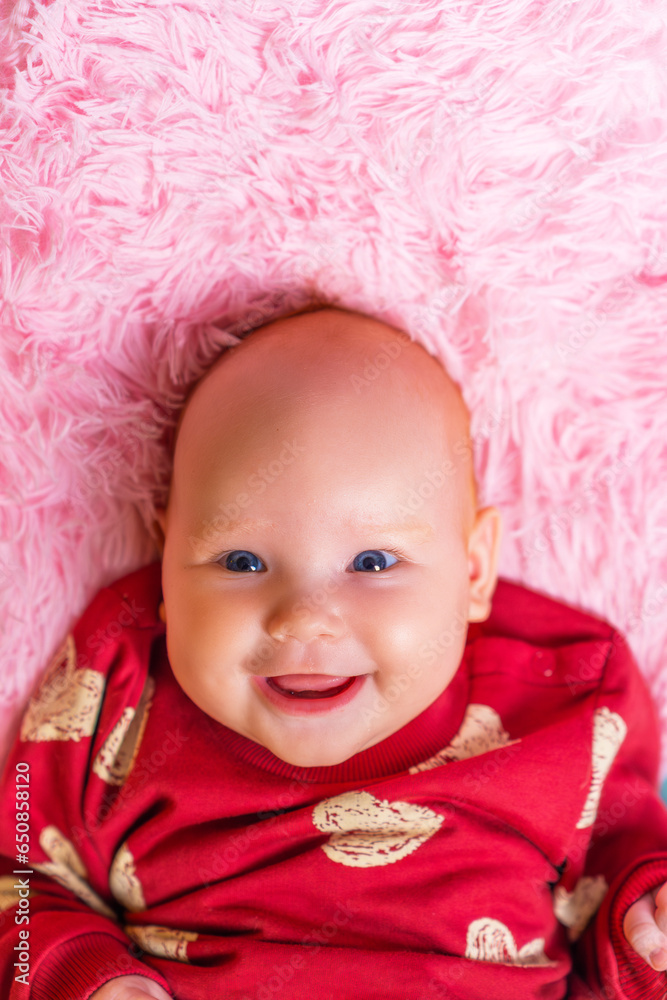 Portrait of a cheerful and smiling newborn girl in a red hoodie on a pink background Portrait of a cheerful and smiling newborn girl in a red hoodie on a pink background