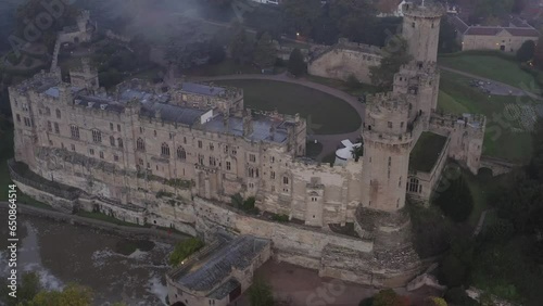 Aerial view of Warwick Castle medieval strongholdand River Avon in foggy evening, famous architectural landmark in England, UK photo