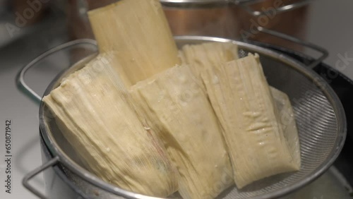 This video shows hands places tamales in a pot steamer.