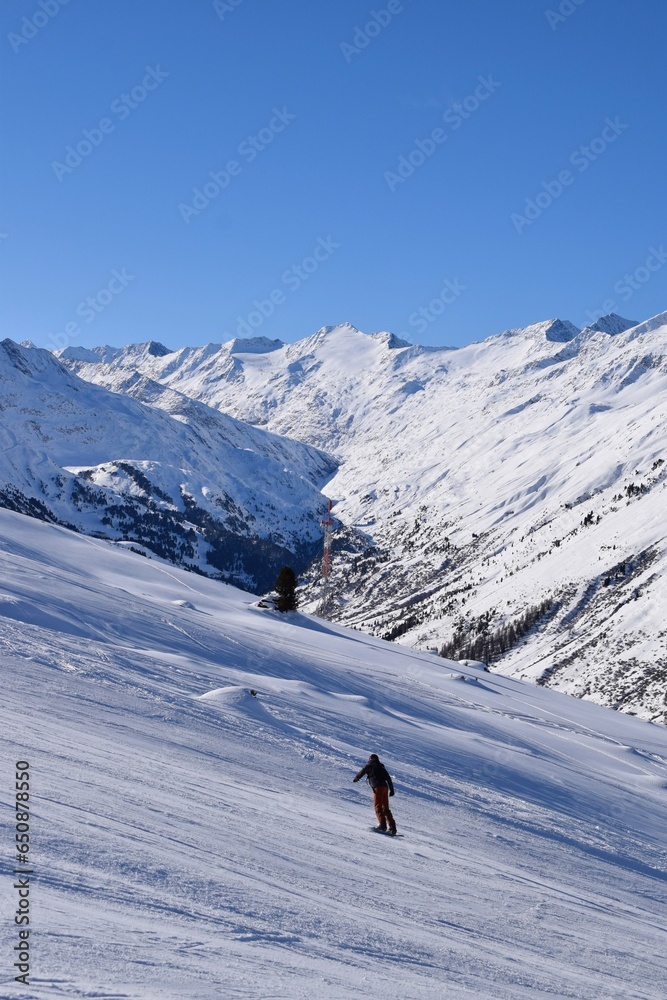 Skiers and snowboarders in Hochgurgl ski resort, backdropped by the Ötztal valley and the snow capped alpine mountains in Tyrol, Austria on a beautiful sunny day, perfect conditions for winter sports. Skiers and snowboarders in Hochgurgl ski resort, backdropped by the Ötztal valley and the snow capped alpine mountains in Tyrol, Austria on a beautiful sunny day, perfect conditions for winter sports.