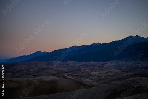Picturesque view of a mountain range and surrounding desert landscape illuminated by the setting sun