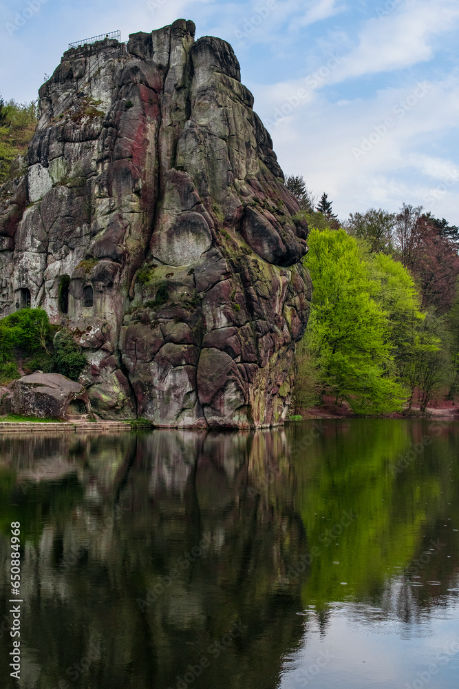 View of a rocky hill and the reflection on the lake in Externsteine, Germany