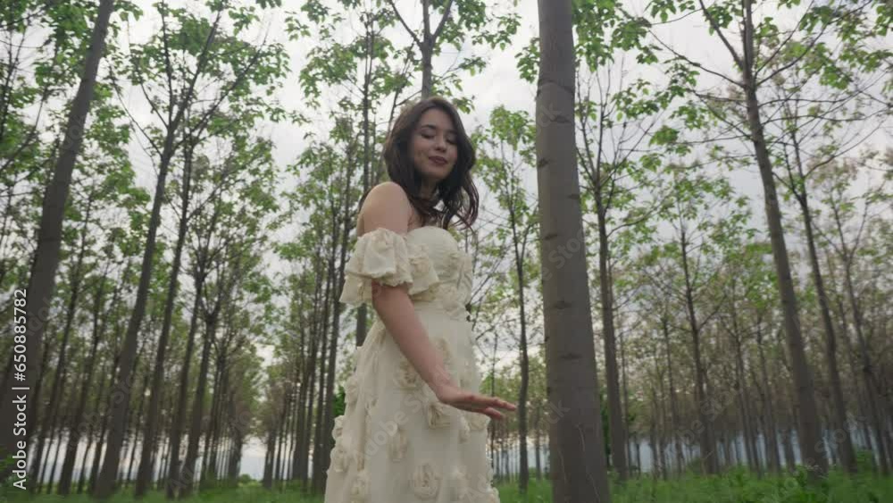 Beautiful Caucasian girl in Off Shoulder white dress under high forest trees Beautiful Caucasian girl in Off Shoulder white dress under high forest trees