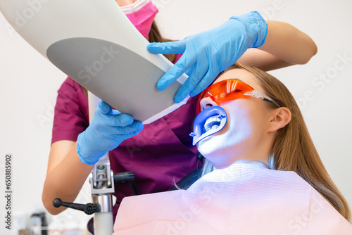 Foto A woman undergoes teeth whitening and the application of a UV lamp for the bleaching process