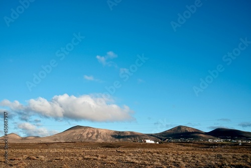 an empty field with dirt and mountains in the distance, in the far distance,