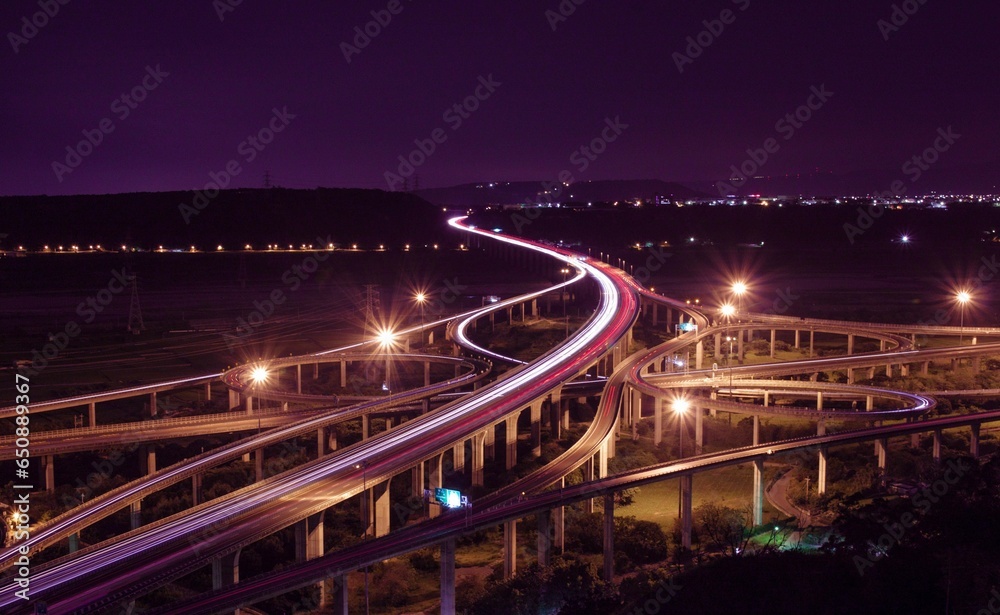 Long exposure nighttime shot of a long winding road with multiple bridges spanning its length
