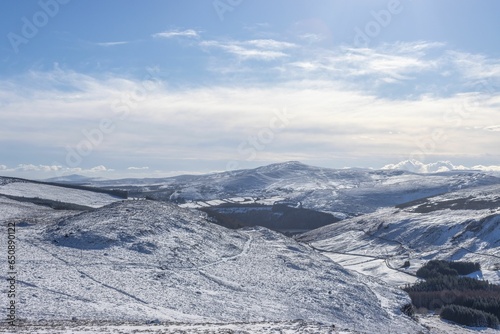 Idyllic winter scene featuring a snow-covered mountain range in the background © Jakub Szoska/Wirestock Creators